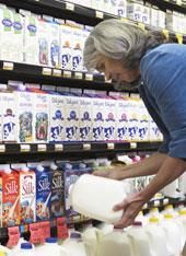 Imagem de mulher no supermercado olhando caixas de leite